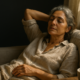 Descansar sin culpa: mujer descansando relajada en un sofá junto a una ventana en una mañana de verano