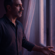 Soltar el rencor: hombre sereno junto a una ventana al amanecer soltando la tensión