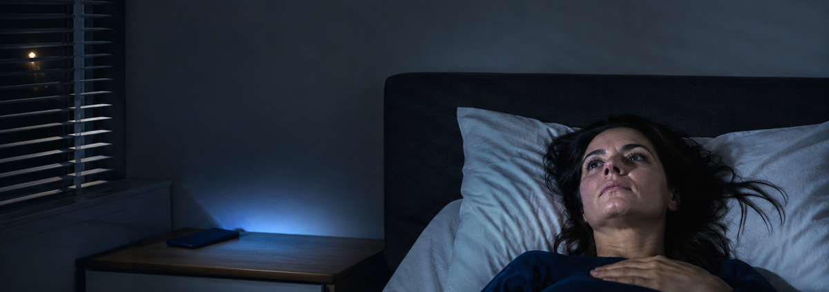 Mujer despierta de madrugada en la cama por cortisol y estrés crónico sostenido