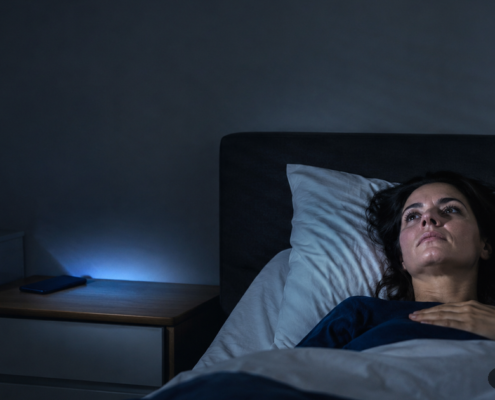 Mujer despierta de madrugada en la cama por cortisol y estrés crónico sostenido
