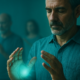 Hombre en una formación energética presencial con las manos abiertas frente al pecho en una sala de piedra