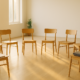 Círculo de doce sillas de madera vacías en una sala luminosa de Vic, preparadas para un retiro espiritual