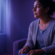 Mujer sentada de noche en el sofá mirando el móvil en silencio, esperando una respuesta: relación intermitente