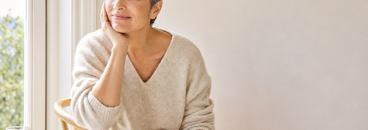 Mujer sonriente comprobando el calor de sus palmas junto a una ventana: sensación de calor en las manos al meditar